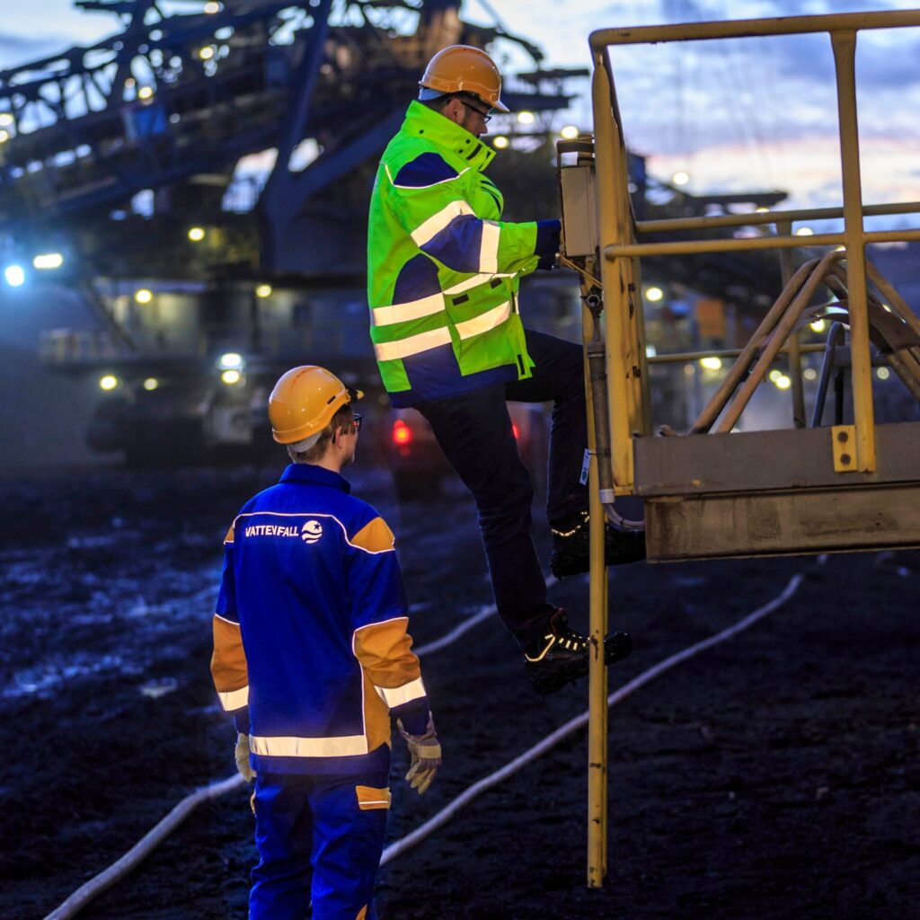 Dois profissionais em local de trabalho usando uniforme com aplicação de faixas refletivas